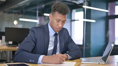 Serious Young Businessman doing Paperwork in Office