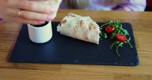 Lady taucht Tortilla in Sauce und bereitet sich darauf vor, in der Pizzeria einen Happen vom Gericht zu essen