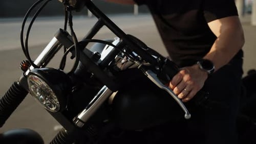 A Motorcycle and a Man in the Summer Black Clothes on a Biker and a Shiny Black Motorcycle Rare