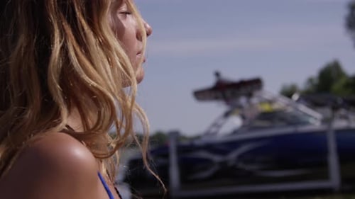 Woman Tilts Head Back Towards Blue Sky by Boat