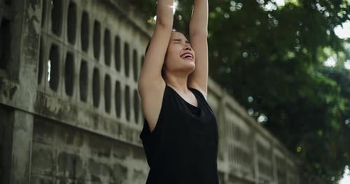 Young Woman Stretching Arms Overhead in Sunlight
