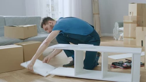 Professional Furniture Assembly Worker Uses Screwdriver to Assemble Shelf. Professional Handyman Do