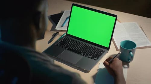 Guy Taking Notes and Using Laptop with Chroma Key Screen