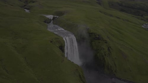 Aerial View of Waterfall Cutting Through Green Hills