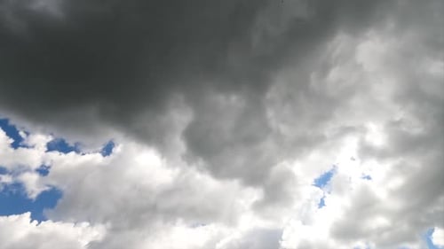 White and grey clouds forming in the blue sky. Rays of sun breaking through the clouds timelapse.