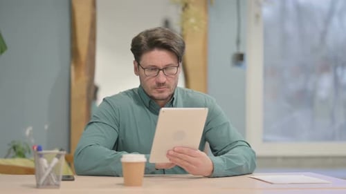 Man Using Tablet at His Desk in Office