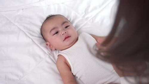 Close up of young biracial mom hold little infant toddler learn walking at home