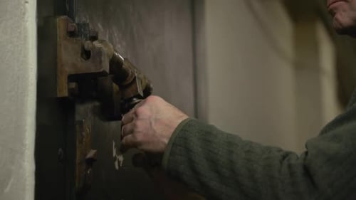 Close up shot of Old Male unlocking old iron rusty door, film tone color.