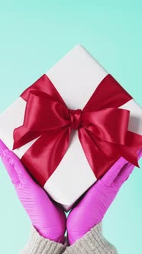 Present Held in Pink Gloves with Red Bow