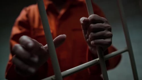 Hands of Inmate Holding Bars of Prison Cell