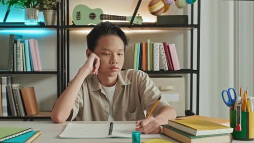 Thoughtful Asian Boy at School Desk