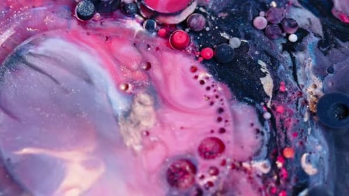 Vivid shot of pink and blue ink swirling in water with bubbles