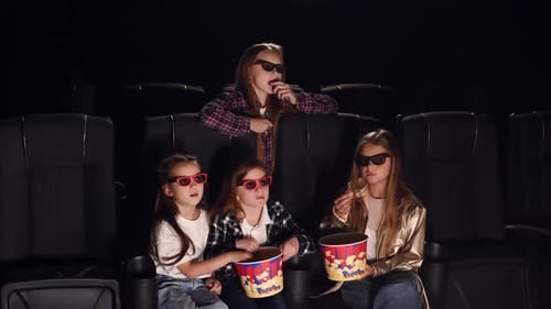 In 3D glasses. Four kids sitting in the cinema and eating popcorn