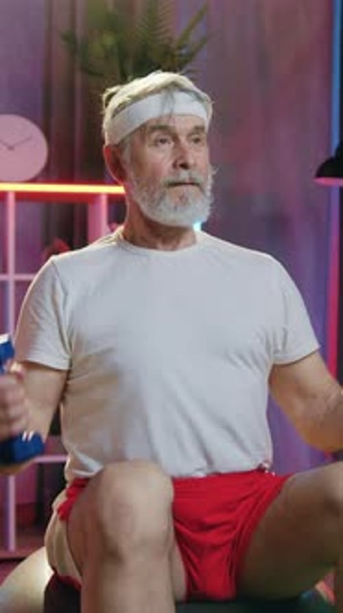 Senior Man Lifting Weights on Exercise Ball at Home