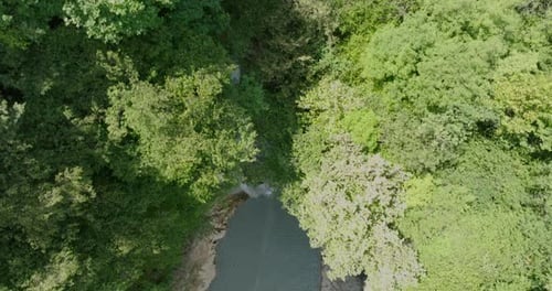 A waterfall falling from a stone cliff in the forest. Aerial view of nature.