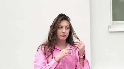 A Playful Woman Holds a Strand of Her Hair with a Whimsical Expression Showing Her Lighthearted and