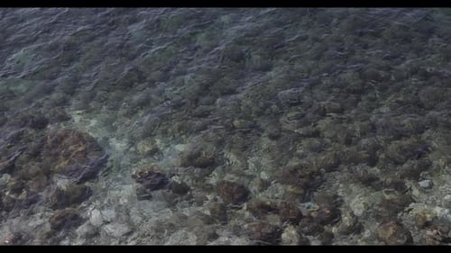 Vista aérea de las olas de un agua azul por encima de las piedras en la parte inferior