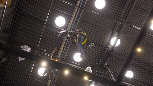 Arbeiter in gelben Westen laufen auf dem Boden des Spanndrahtgitters