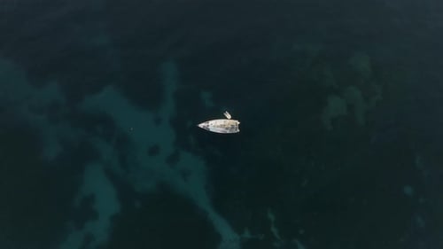 Aerial view of a sailing boat sailing along the coast in Sicily, Italy.