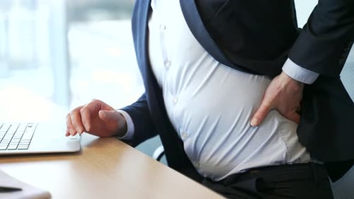 Close up. Male hand holding massaging lower back. Man in a formal suit suffering from back pain