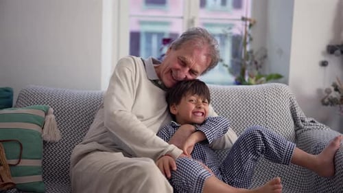 Grandfather and Grandson Cuddling and Laughing on Sofa