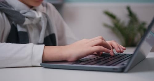 Close-up of hands typing on a computer keyboard student searching information at living room at home