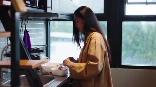 Woman Prepares Food in Well-Lit Kitchen