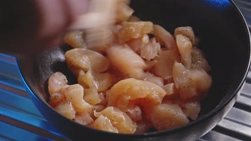 Chicken Pieces Seasoned and Mixed with Wooden Spoon
