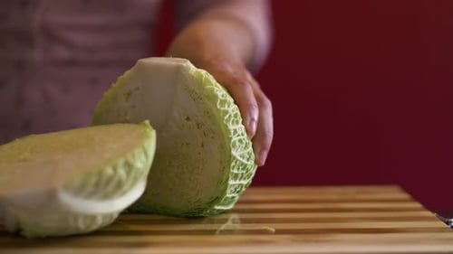 Nahaufnahme von Frauenhänden, die vor dem Kochen einen Wirsing halbieren
