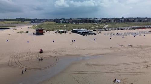 A beautiful aerial view of a sandy beach with rows of beach huts, people relaxing by the shore
