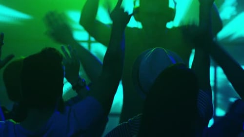 DJ Playing Music in Nightclub, People Dancing, Having Fun and Raising Hands.