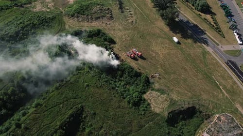 Aerial View of Two Fire Engines are Standing Near Center of Ignition and Clouds of Smoke in
