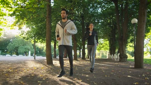 Young Woman and Man Running Together Forward Towards Camera in Bright Sunny Day