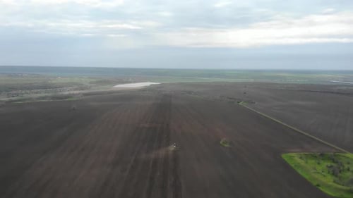 Blue tractor planting sunflower with yellow planter on the field in Ukraine