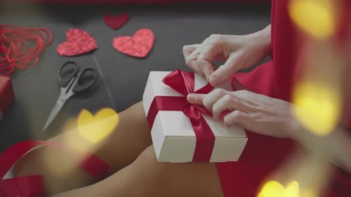 Woman Tying Bow On Wrapped Gift