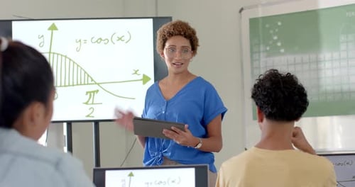 Teaching math, woman using tablet and explaining graph to students in high school