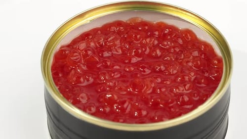 A tin of red caviar rotates on a white background.