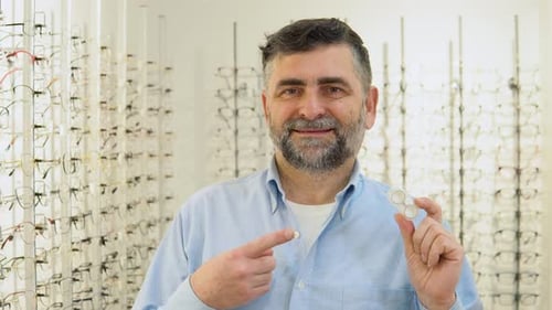 Hombre mayor de 50 años y 60 sostiene lentes de contacto en las manos