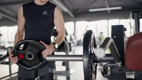 Focused Man Adjusting Weights for Workout in Modern Gym