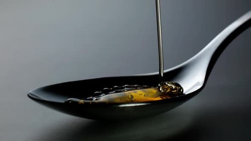 Honey poured into shiny spoon, minimal, making patterns in slow motion