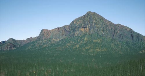 View of a Rugged Mountain Peak Surrounded By Dense Evergreen Forest
