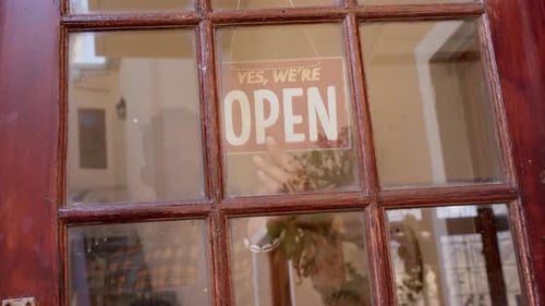 African american male business owner changing shop sign to open, slow motion
