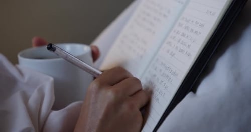 Person Journaling in Bed with Mug Close Up