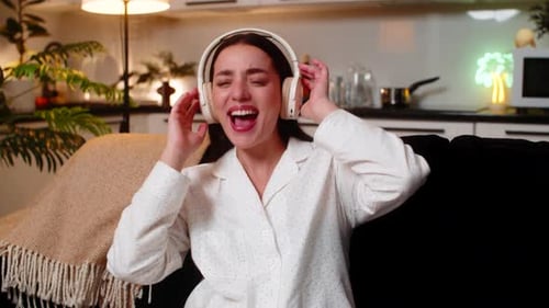 Young Woman Hears Song in Headphones Starts Seated Dance Rock Moves Laughs Cheers Yeah Energy Wild