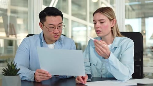Group of Two People Discussing New Project While Sitting at Desk in Office