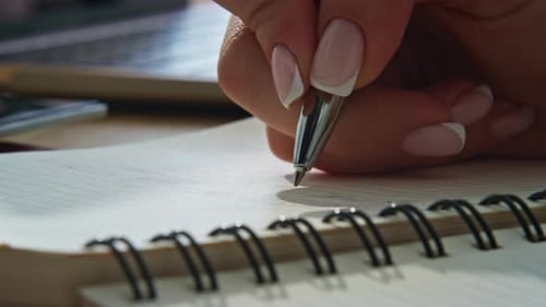 Hand Writing in Notebook on Desk with Laptop