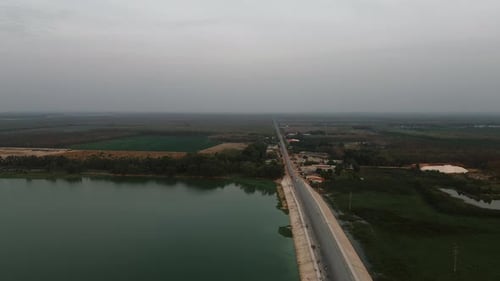Aerial view of a lonely road alongside a lake, offering a peaceful rural setting