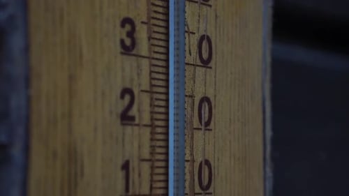 Celsiusthermometer aus Holz mit blauer Skala und Hirschzeichnung auf der Oberseite bei kaltem Wetter. Langsame vertikale Kamera