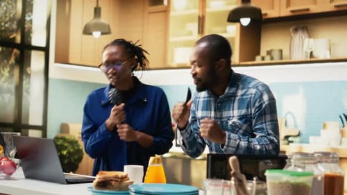 Cheerful Couple Dancing and Singing in Modern Kitchen