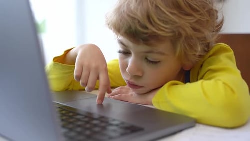 Child Using Laptop Trackpad at Home, Looks Tired